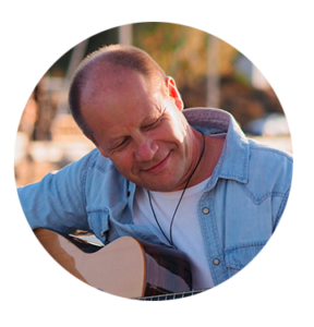 Pyöreä kuva missä mies hymyilee kitara kädessä.